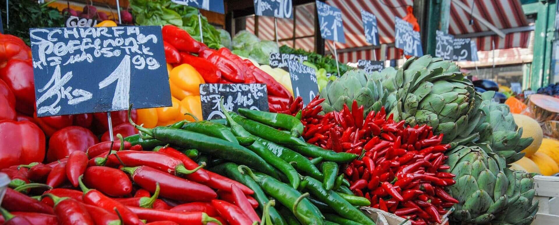 Auf diesem Bild ist ein Gemüsestand auf einem Markt zu sehen.