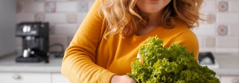 Dieses Bild zeigt eine Frau, die ihren Einkauf an gesunden Lebensmitteln in Ihrer Küche auspackt. In diesem Blog-Artikel erfahren Sie 5 Tricks wie Sie in Ihrem Alltag automatisch gesünder essen.