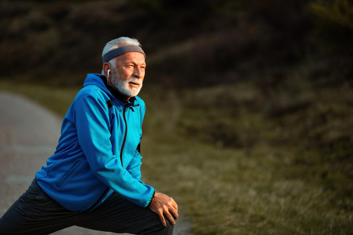 Dieses Foto zeigt einen fitten alten Mann, der gerade eine aktive Pause vom Joggen einlegt. Man sieht, dass er schon früh damit begonnen hat, langfristig in seine Gesundheit und Fitness zu investieren.